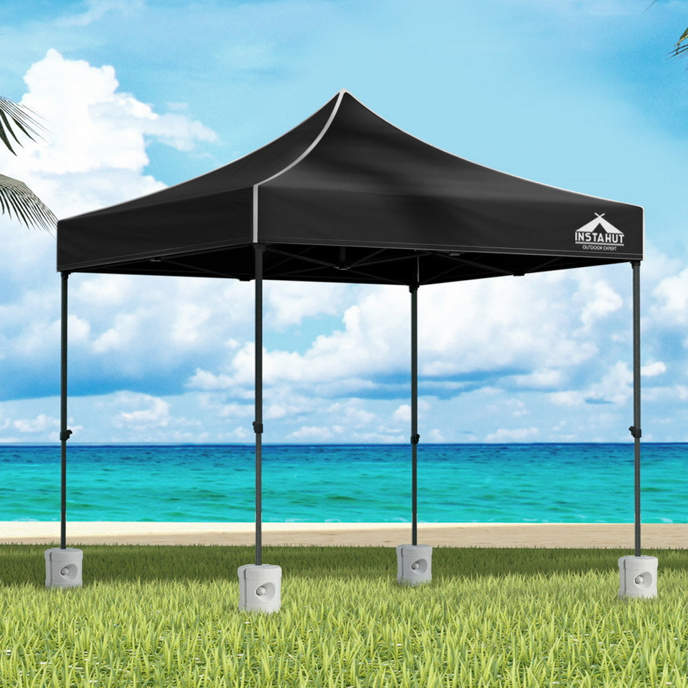 Black 3 x 3 m pop up gazebo with four base pods set up outdoors