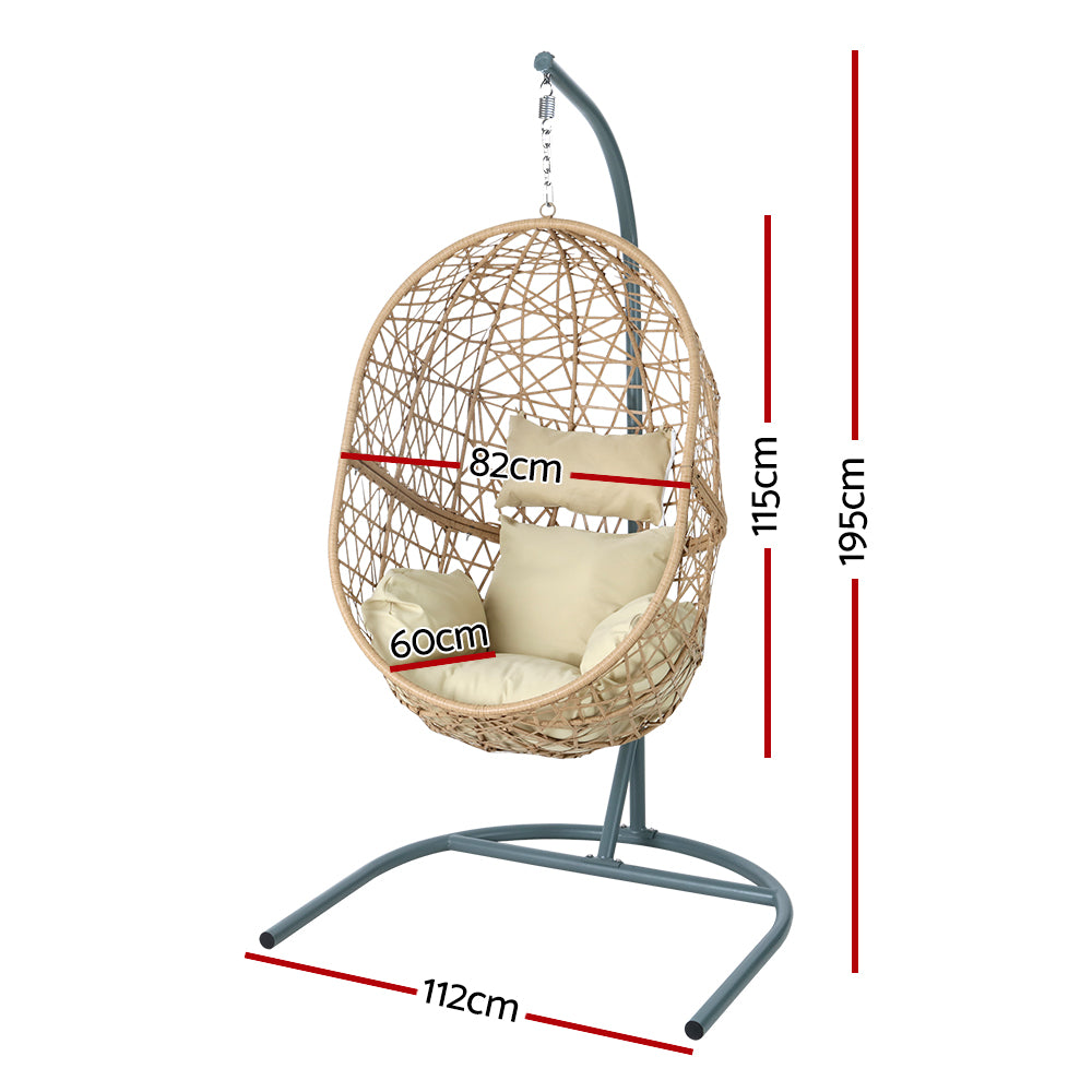 Vincentia yellow resin wicker hanging egg chair with stand on a patio