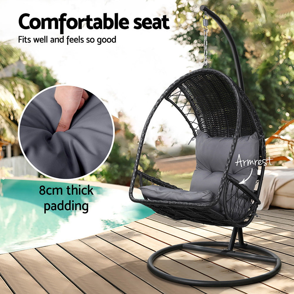 Gerroa black resin wicker hanging egg chair with stand on a patio