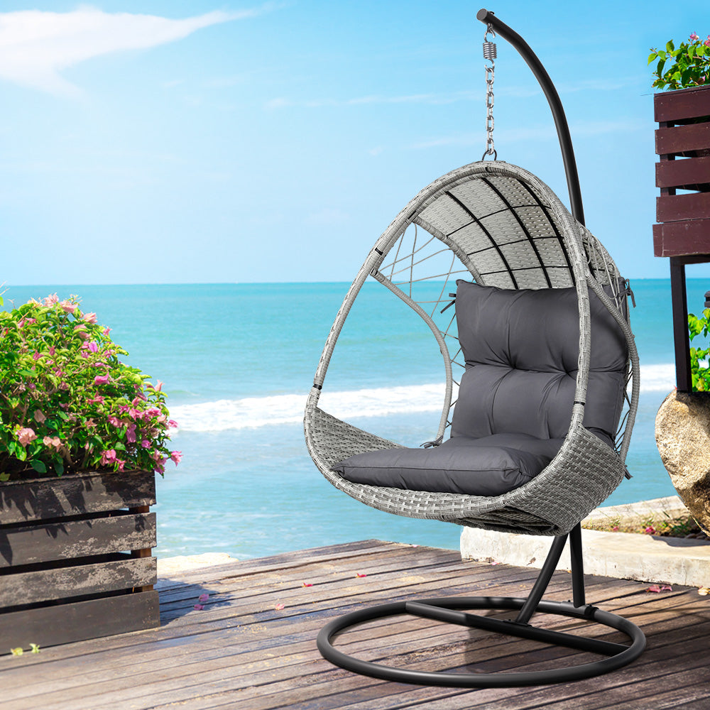 Gerroa light grey resin wicker hanging egg chair with stand on a patio
