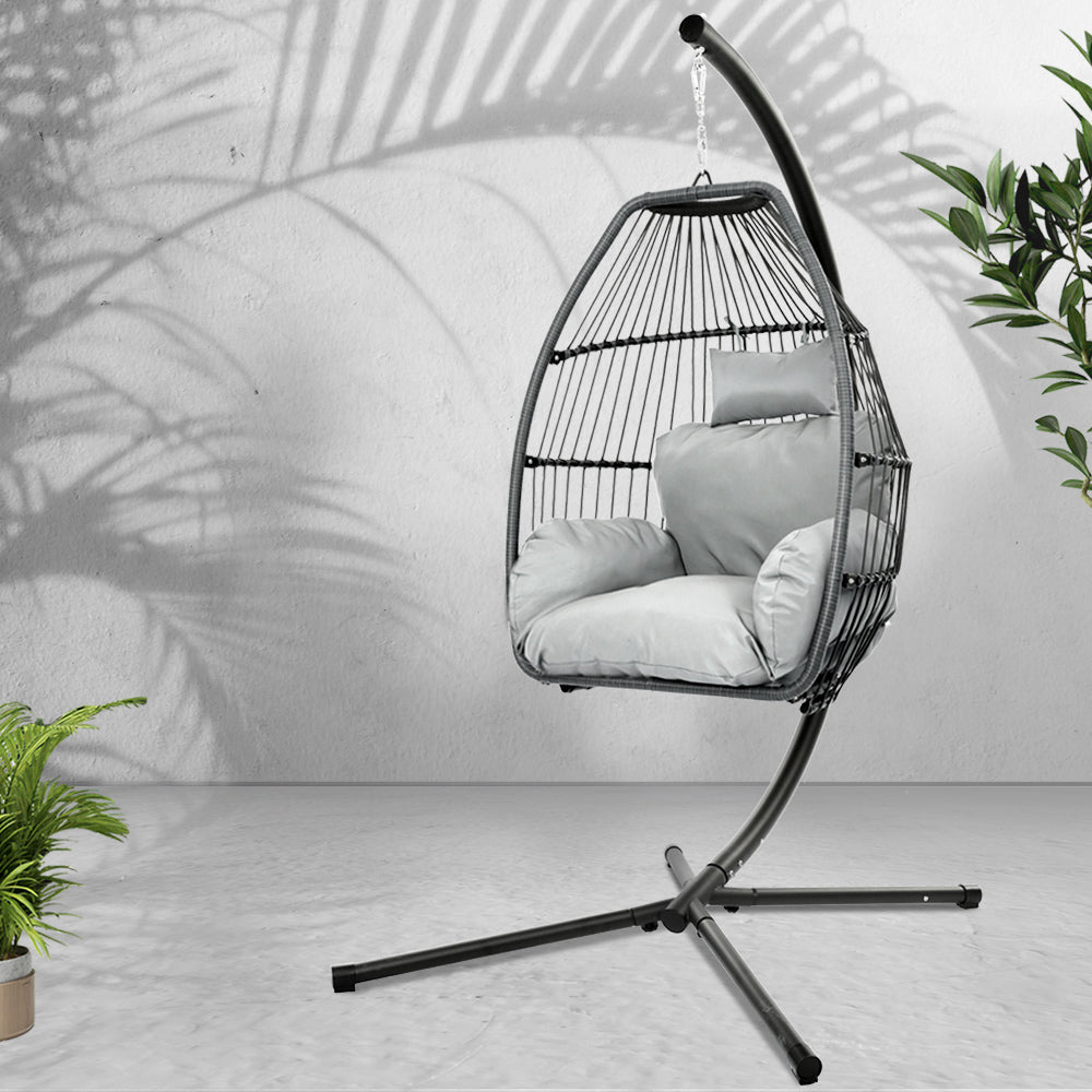 Sussex Inlet grey hand woven wicker hanging egg chair with stand on a patio
