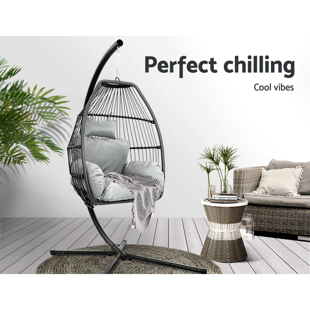 Sussex Inlet grey hand woven wicker hanging egg chair with stand on a patio