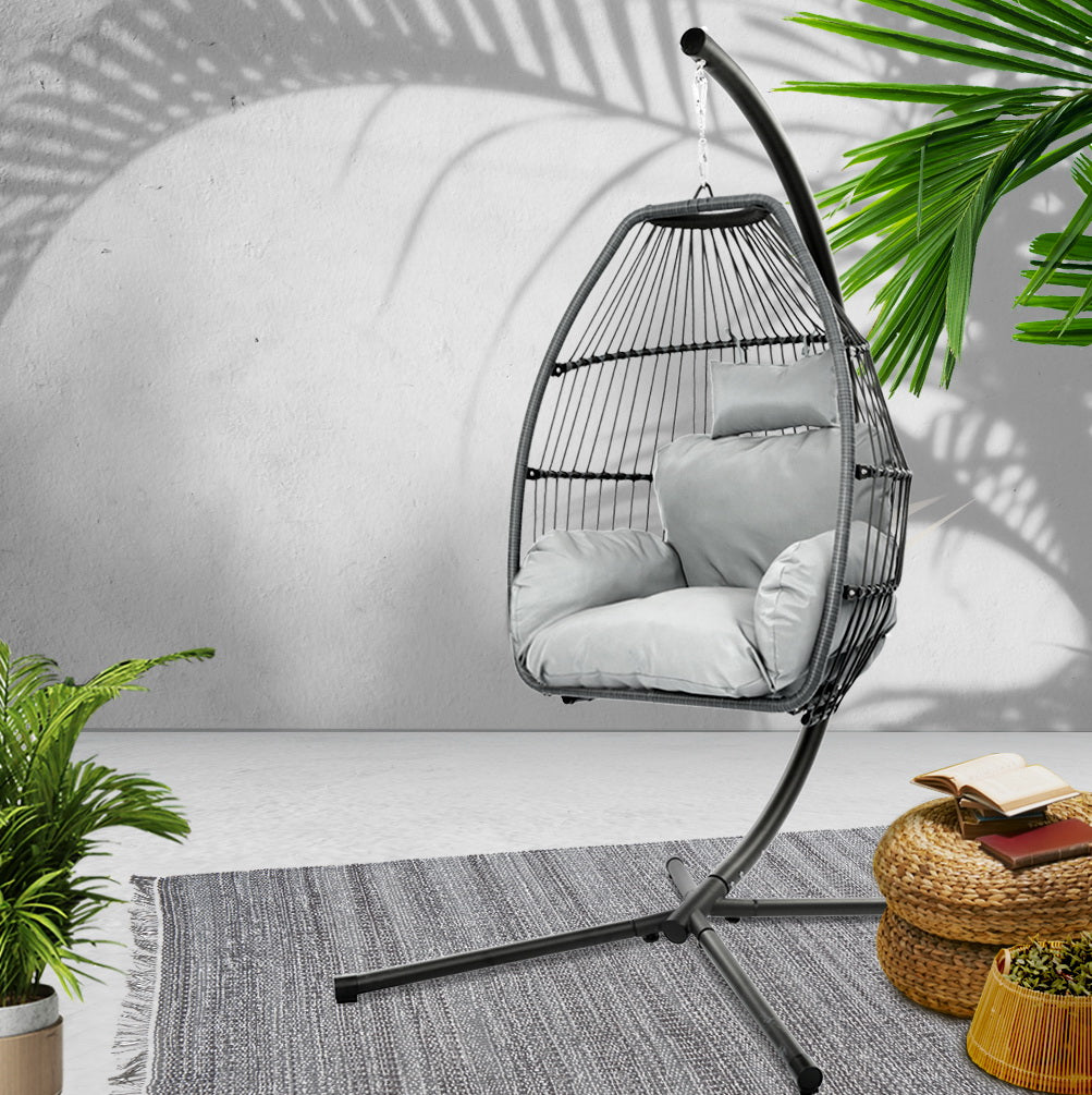 Sussex Inlet grey hand woven wicker hanging egg chair with stand on a patio