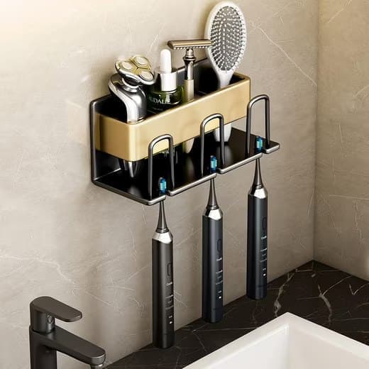 Gold wall mounted rack holding three toothbrushes in its slots with the cup below
