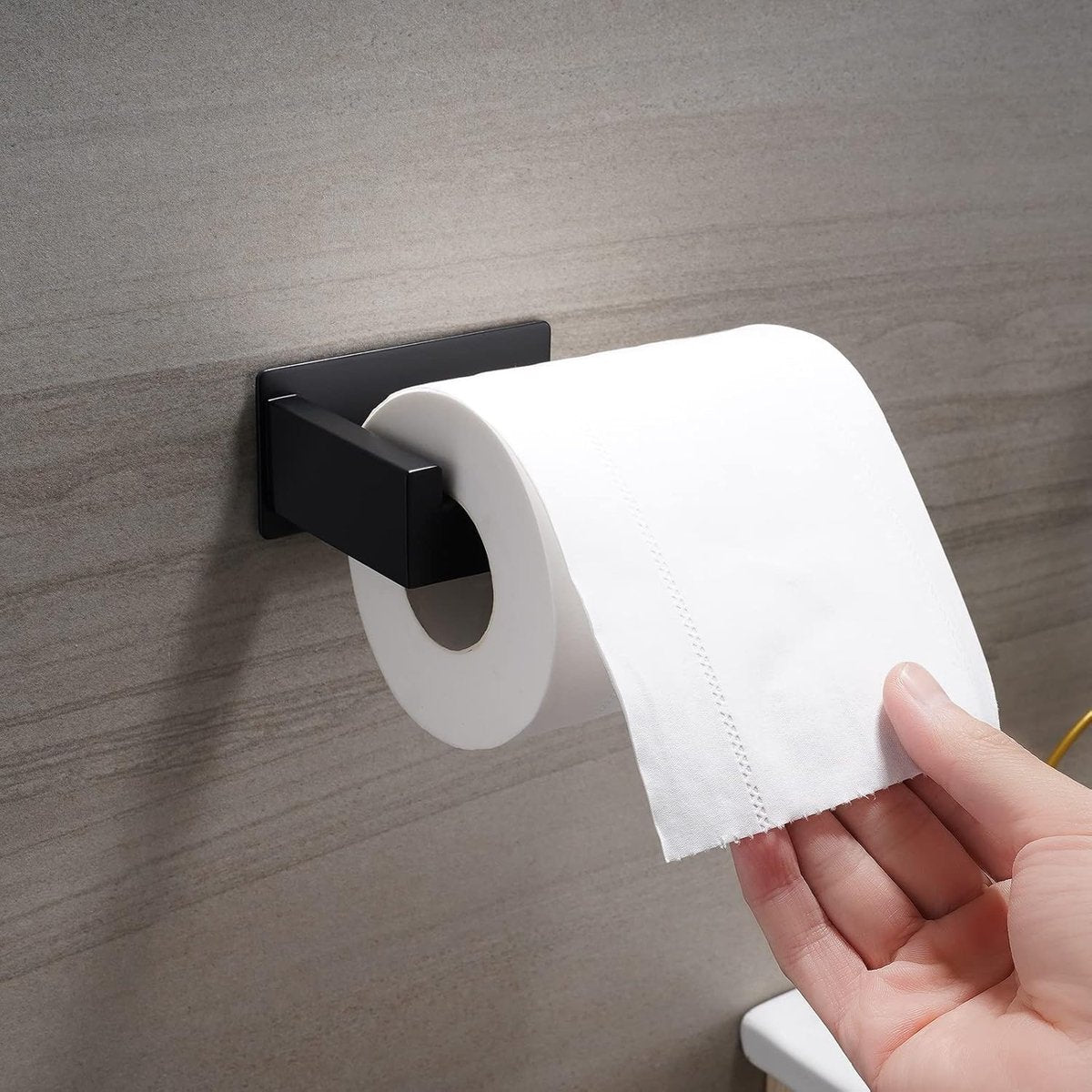 Adhesive pad on the back of the black toilet paper holder