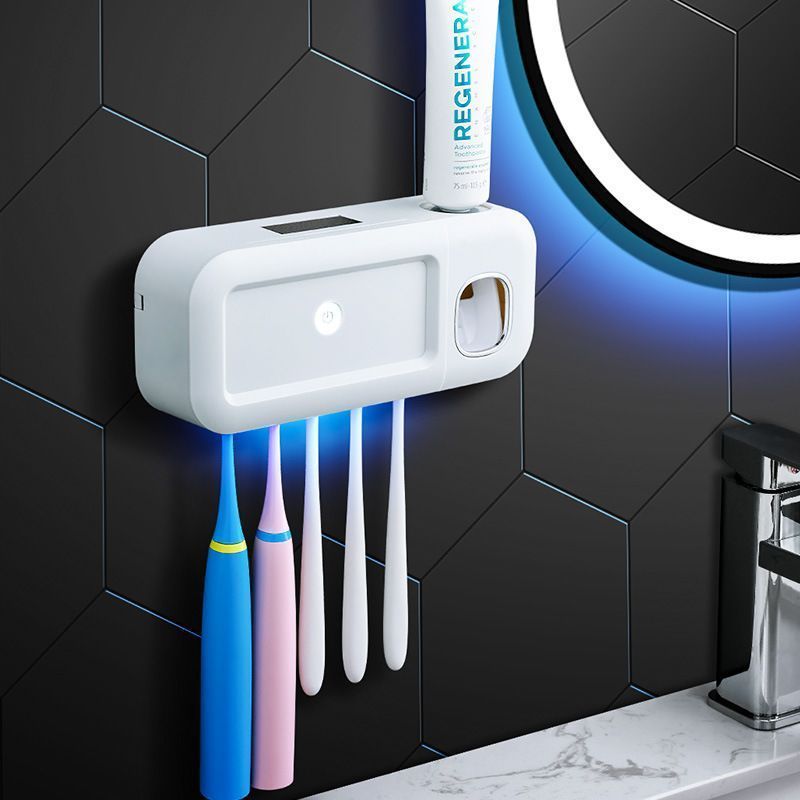 Grey toothbrush holder mounted on bathroom tiles holding five toothbrushes