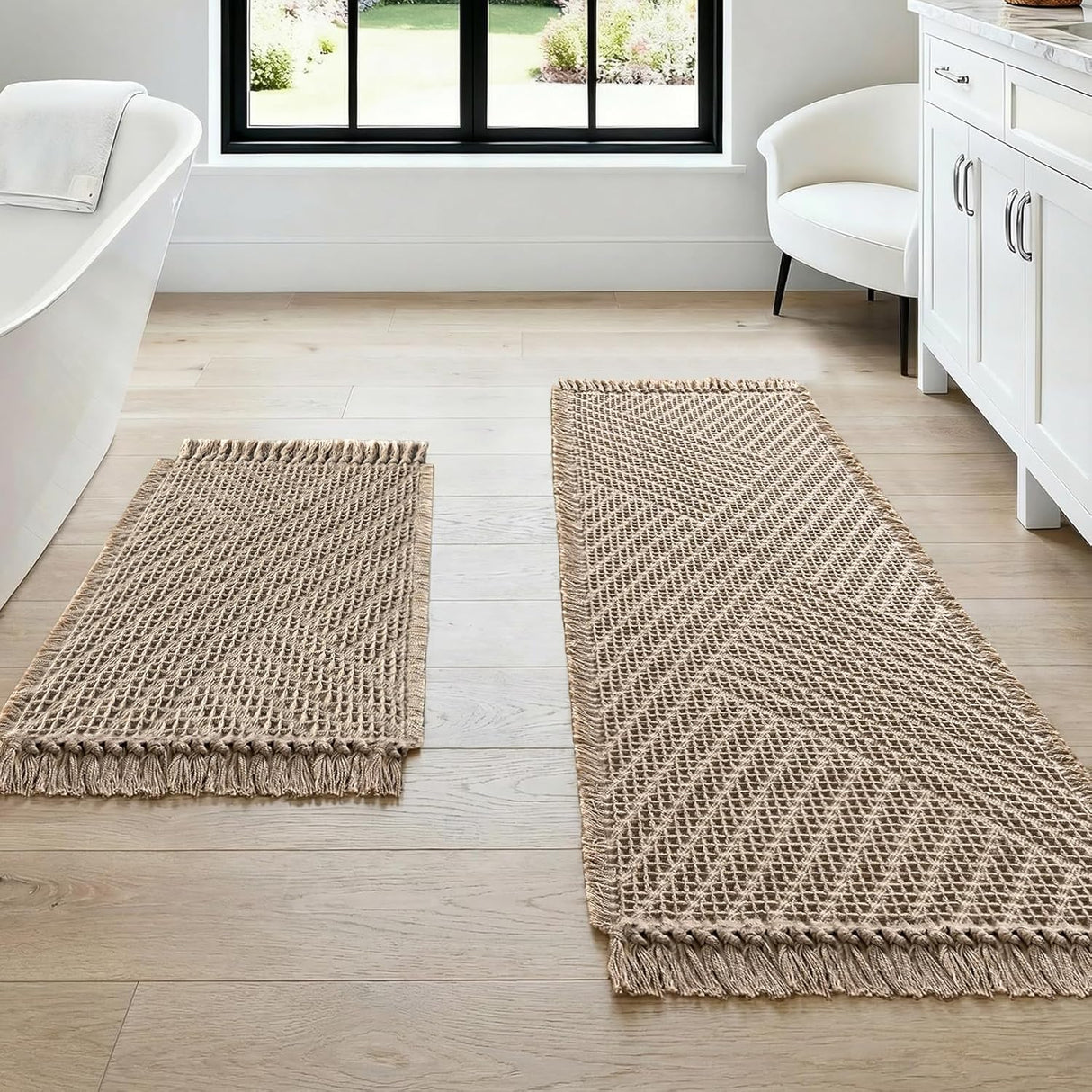Cream waffle bath mat set of two with tassels laid on a bathroom floor
