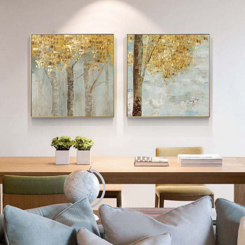 Pair of gold framed golden leaves canvases hanging above a sofa