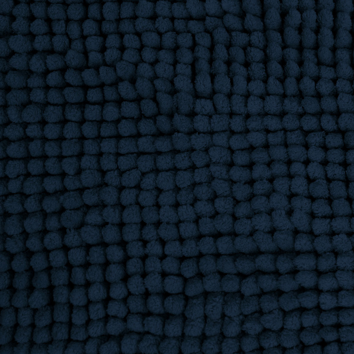Navy microfibre bath mat shown beside a bath with its non slip backing on tile