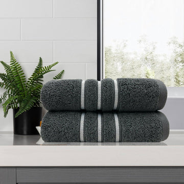 Two charcoal 650 GSM cotton bath towels, 68 x 137 cm, folded to show the contrasting dobby stripe border