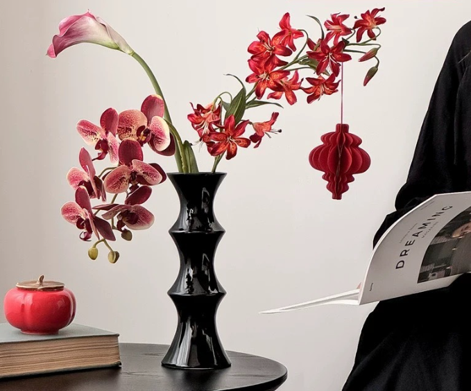 Tall glossy black bamboo form ceramic vase on a dining table