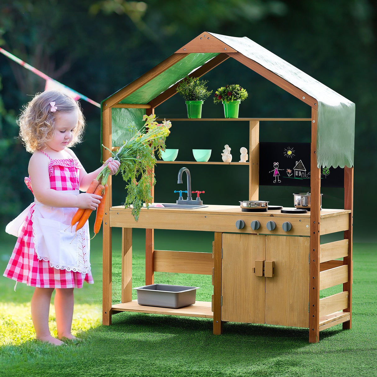 Child playing at wooden mud kitchen outdoors
