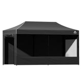 Black gazebo packed down beside its wheeled carry bag ready for transport