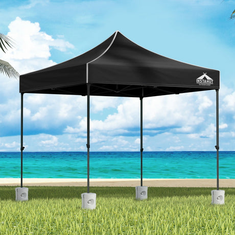Black 3 x 3 m pop up gazebo with four base pods set up outdoors
