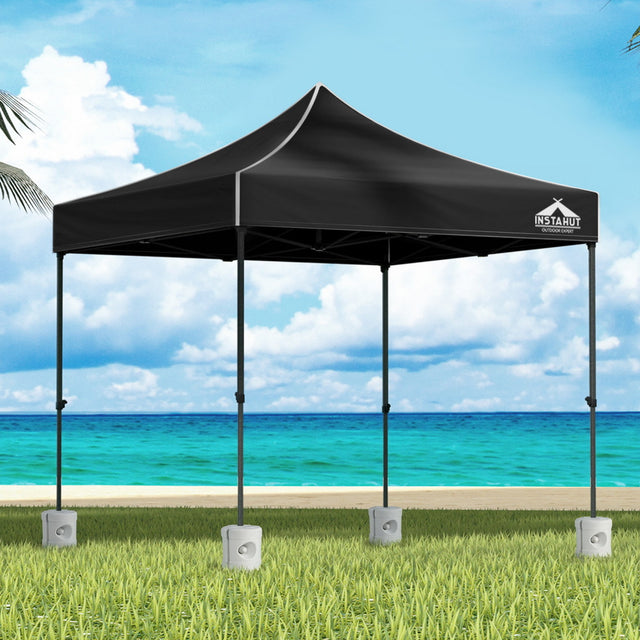 Black 3 x 3 m pop up gazebo with four base pods set up outdoors