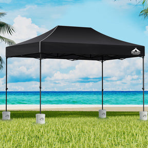 Black 4.5 x 3 m pop up gazebo set up outdoors with white base pods on the legs