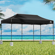 Black 6 x 3 m pop up gazebo set up outdoors with white base pods on the legs