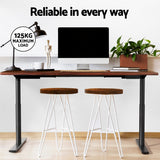 Braddon rustic brown electric standing desk with black frame in a home office