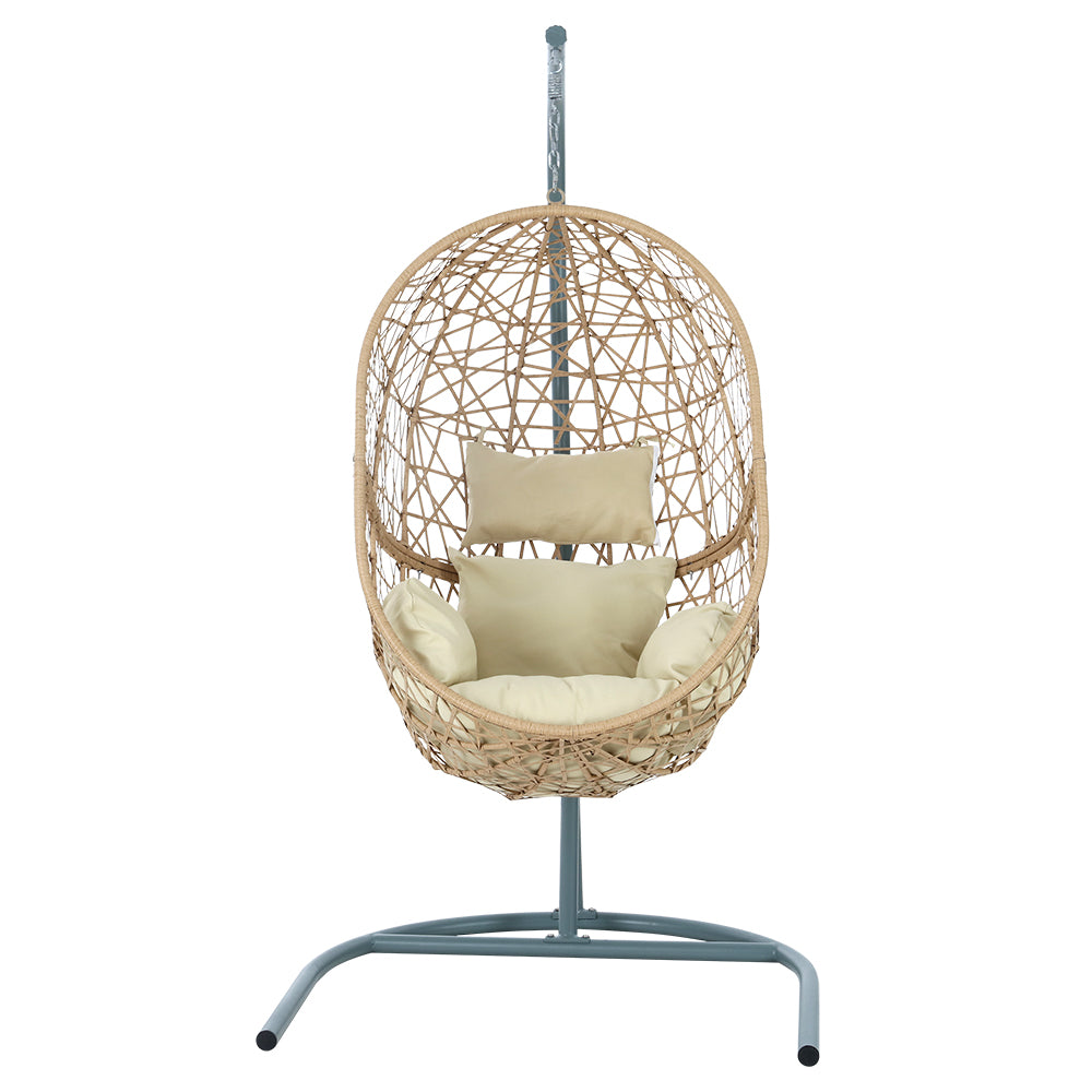 Vincentia yellow resin wicker hanging egg chair with stand on a patio