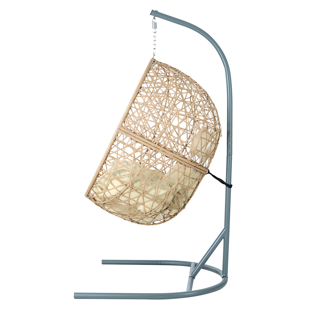 Vincentia yellow resin wicker hanging egg chair with stand on a patio