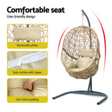 Vincentia yellow resin wicker hanging egg chair with stand on a patio