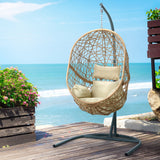 Vincentia yellow resin wicker hanging egg chair with stand on a patio