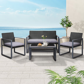 Eden black rattan outdoor sofa set with plush cushions and tempered glass table on a balcony