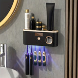 Olbia wall mounted toothbrush organiser in black and gold with toothpaste dispenser
