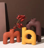Three graduated tubular letter form ceramic vases in a matte finish