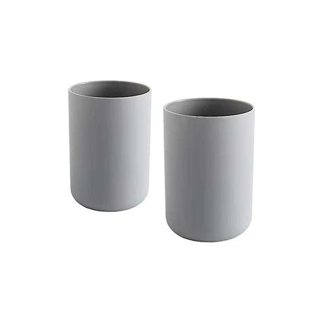 Two grey plastic toothbrush cups standing side by side on a bathroom vanity