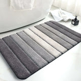 Grey microfibre bath mat on a tiled bathroom floor beside a shower