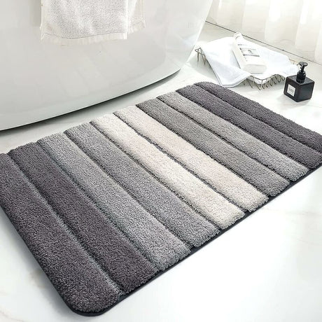 Grey microfibre bath mat on a tiled bathroom floor beside a shower
