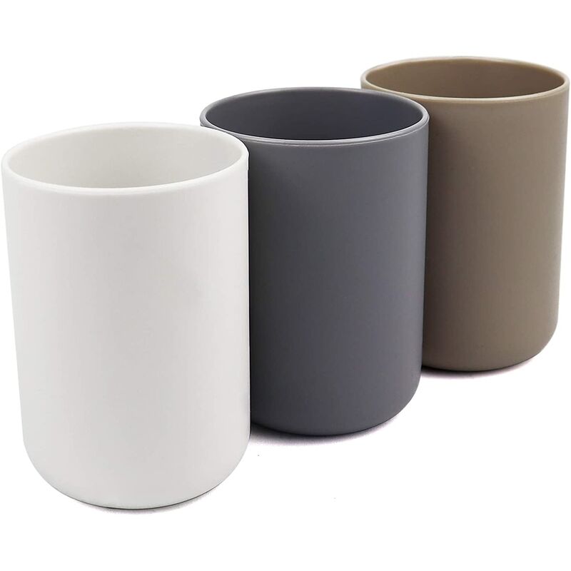Three matte bathroom tumblers in white, grey and brown standing together on a vanity