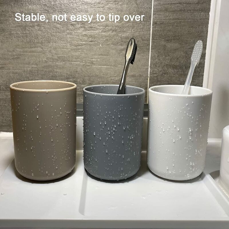 Bathroom tumblers holding toothbrushes and a tube of toothpaste beside a basin