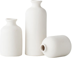 Three tall graduated white ceramic vases with an architectural form