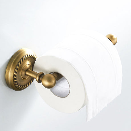 Brass toilet roll holder mounted on a bathroom wall beside a toilet
