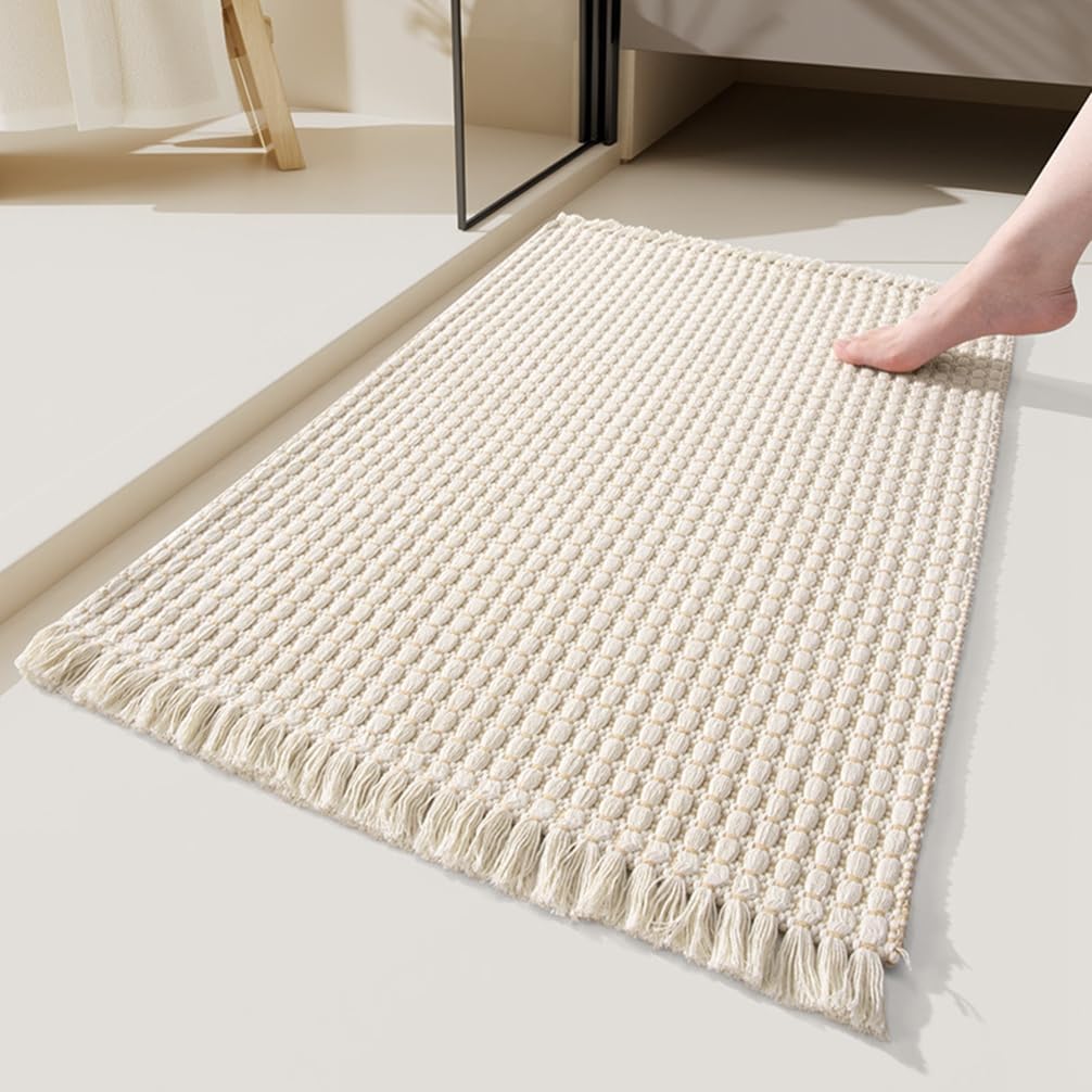 Beige tufted microfibre bath mat, 51 x 81 cm, with braided weave and tassel trim