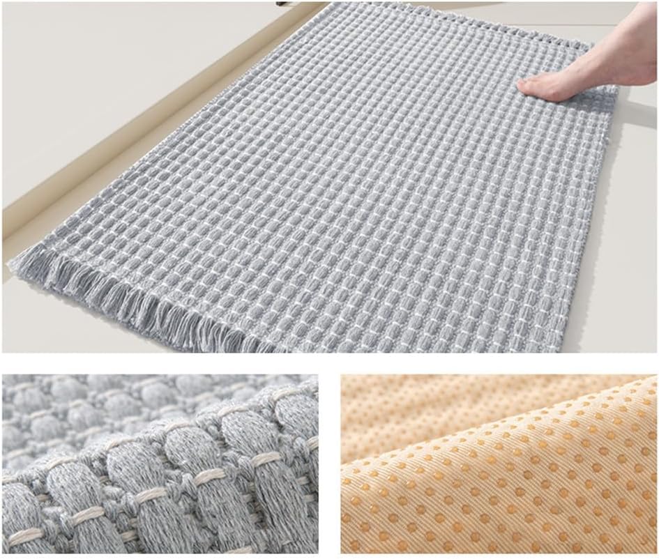 Beige braided bath mat placed beside a bath on a tiled bathroom floor