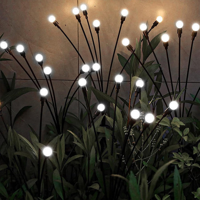 Cool white solar firefly lights swaying among garden planters at night
