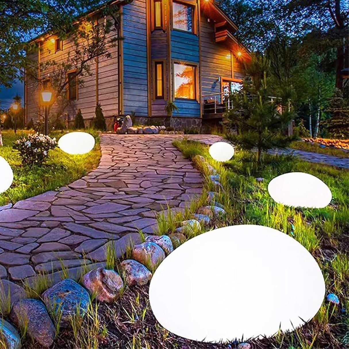 Solar cobblestone shaped garden light glowing in a flower bed