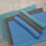 Two pack of white absorbent cotton bath mats folded and stacked