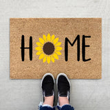 Floral entrance door mat with blue blooms and green foliage on brown