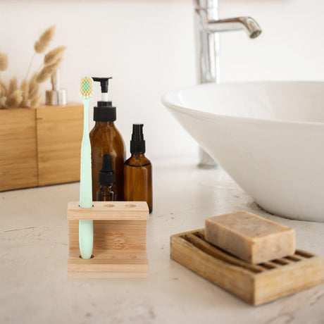 Khaki bamboo toothbrush holder with three compartments on a bathroom counter