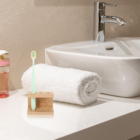 Khaki bamboo organiser beside a basin with a comb and brushes