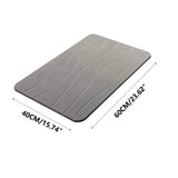 Water absorbing quickly into the surface of the grey diatomaceous earth bath mat