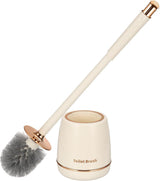 Gold toilet brush and holder set standing beside a toilet