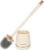 Gold toilet brush and holder set standing beside a toilet
