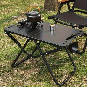 Black folding camp table with iron frame open on grass
