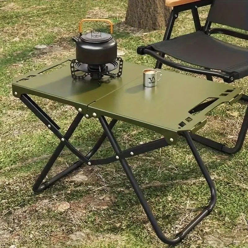Green folding camp table with iron frame open and ready for outdoor use