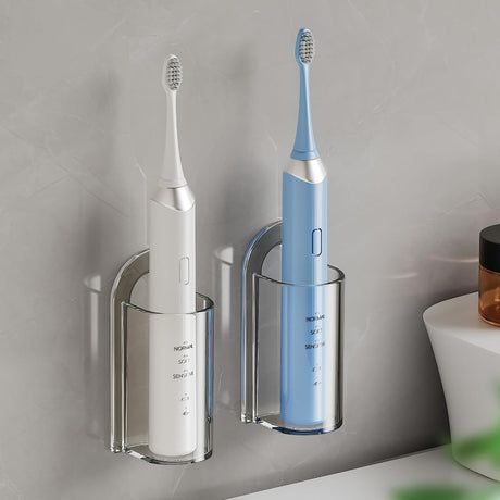 Transparent electric toothbrush holder wall mounted in a bathroom with a toothbrush handle standing upright inside